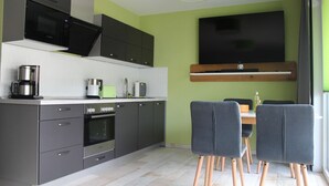 A modern kitchen with a built-in microwave, coffee maker, and toaster. There is a dining area with a table and chairs.