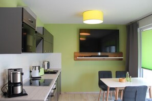 A modern kitchen with a built-in microwave, coffee maker, and a dining area with a table and chairs.