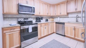 Una cocina moderna con armarios de madera, electrodomésticos de acero inoxidable y salpicadero de azulejos.