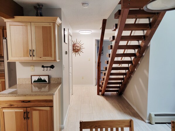 A kitchen with wooden cabinets, a granite countertop, and a sun decoration on the wall.