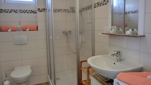 Une salle de bain avec une douche à parois de verre, des toilettes, un lavabo et un miroir.