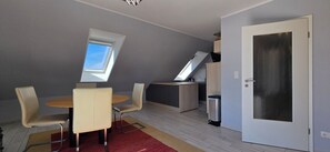 Um espaço compacto para viver, com área de refeições, cozinha compacta e porta com painel de vidro jateado.