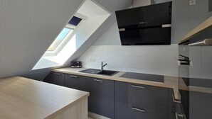 Et moderne køkken med ovenlys, mørke skabe og stålstål-hvidevarer.