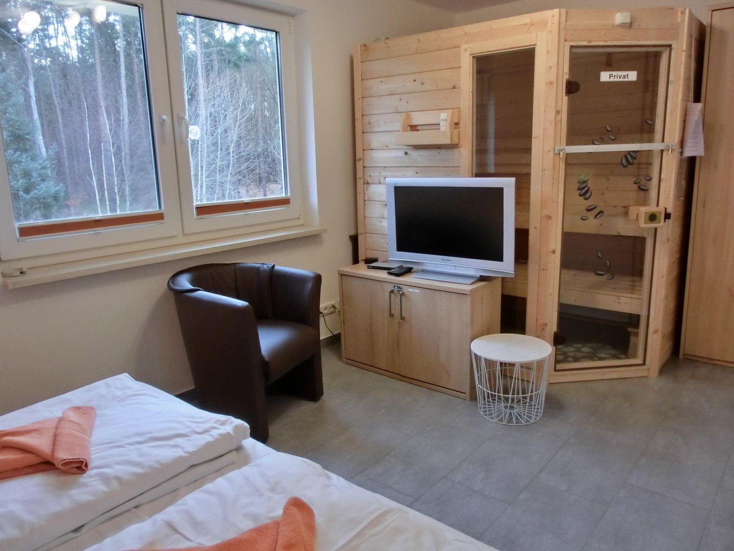 Una habitación con una cama, una silla, un televisor y un armario.