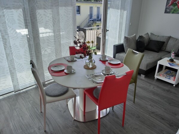 A dining area with a round table set for two, a sofa, and a small side table with a magazine.