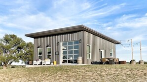 A modern building with large windows and a flat roof, surrounded by a grassy area and trees.
