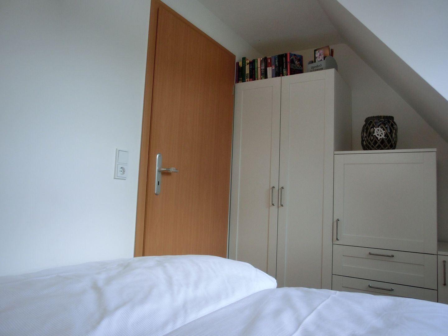 Quarto com cama, guarda-roupa e pequeno armário.