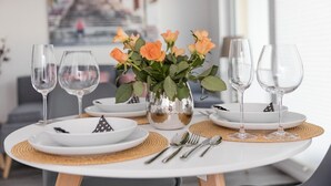 A dining table set with white plates, silverware, and empty wine glasses, accompanied by a vase of orange roses. - Apartment KWi 83 ground floor "Casa Baltico" - 2-room apartment for 3 pers. with WLAN (Gelbensande)