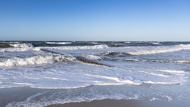 A beach with waves crashing onto the shore and a wooden barrier separating the water from the sand. - Apartment KWi 83 ground floor "Casa Baltico" - 2-room apartment for 3 pers. with WLAN (Gelbensande)