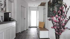 A hallway with a bench, a vase with flowers, and a door leading to a bright room. - Apartment KWi 83 ground floor "Casa Baltico" - 2-room apartment for 3 pers. with WLAN (Gelbensande)