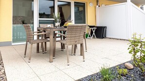 A patio with a table and chairs, a small garden area with plants, and a white fence. - Apartment KWi 83 ground floor "Casa Baltico" - 2-room apartment for 3 pers. with WLAN (Gelbensande)