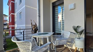 A balcony with wicker chairs and a table, a potted plant, and a view of neighboring buildings. - Vacation apartment LP14 - 1-room vacation apartment with approx. 19 m² living space and balcony (Graal-Müritz)
