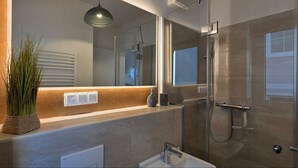A modern bathroom with a large mirror, a shower, and a sink. - Vacation apartment LP14 - 1-room vacation apartment with approx. 19 m² living space and balcony (Graal-Müritz)