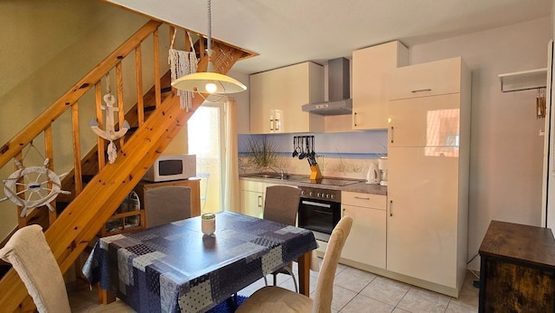 Una cocina compacta con armarios de madera, una estufa y un comedor con mesa y sillas.