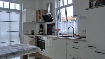 Eine moderne Küche mit weißen Schränken, einem eingebauten Backofen, einer Kaffeemaschine und einem Fenster mit Blick hinaus.