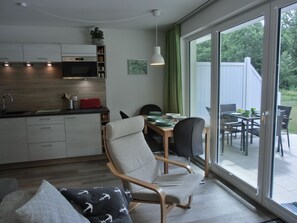 Una cucina moderna con forno a microonde, mobili e zona pranzo con tavolo e sedie.