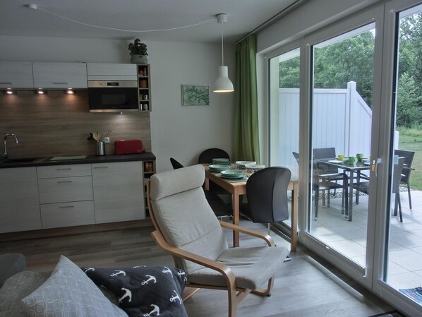 A modern kitchen with a microwave, cabinets, and a dining area with a table and chairs.
