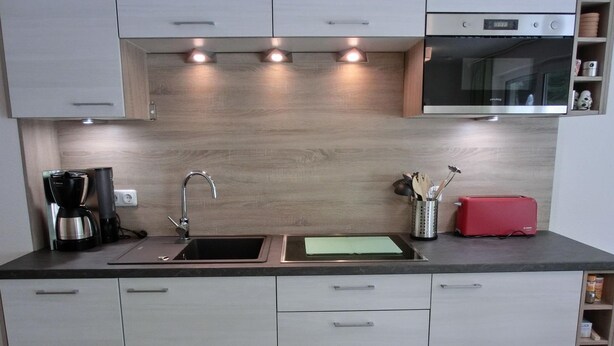 Una cocina moderna con microondas integrado, cafetera y tostadora.