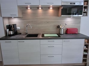 Una cocina moderna con microondas integrado, cafetera y tostadora.