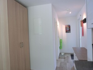 Un corridoio con un armadio in legno, una porta bianca, un oggetto verde e una piccola finestra.