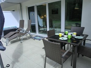 An outdoor patio area with a table set for dining, surrounded by wicker chairs.