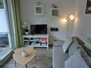 A modern living room with a flat-screen TV, bookshelves, a sofa, and a floor lamp.