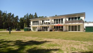A two-story building with a flat roof, large windows, and a balcony.