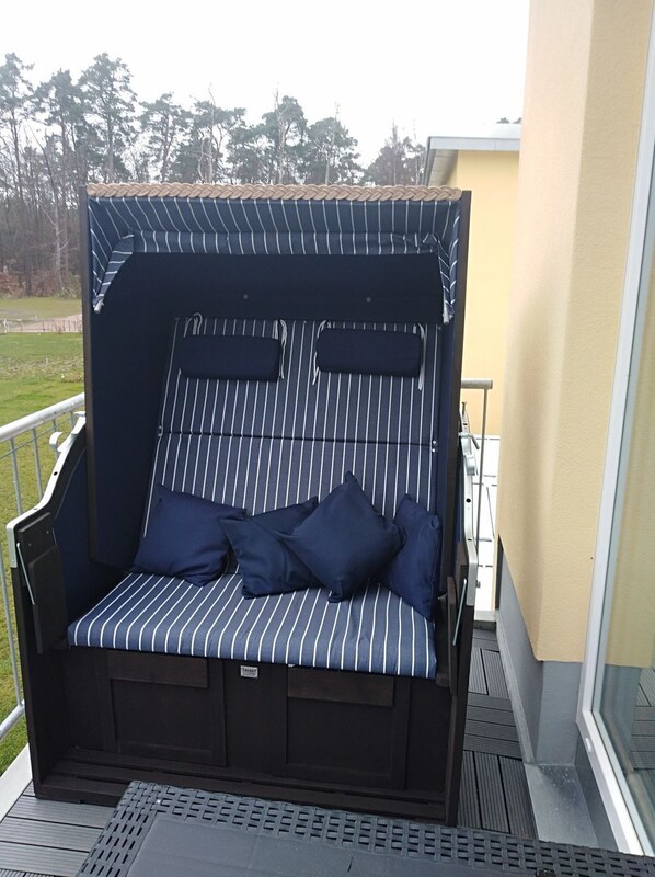 A striped outdoor sofa with cushions on a balcony.