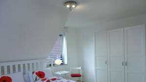 A bedroom with a bed, a desk, and a wardrobe.