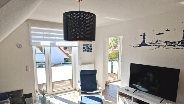 A modern living room with a TV, a glass coffee table, a blue chair, and a white cabinet.