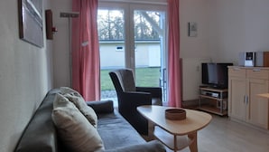 Olohuoneessa on sohva, nojatuoli, pieni pöytä, televisio ja kaappi.