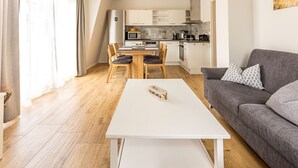 Un soggiorno moderno con un tavolino bianco, un divano grigio e un'area pranzo con sedie di legno e un tavolo bianco.