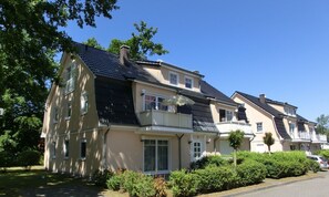 Un immeuble résidentiel de deux étages doté d’un balcon, d’un porche couvert et d’un jardin bien entretenu.