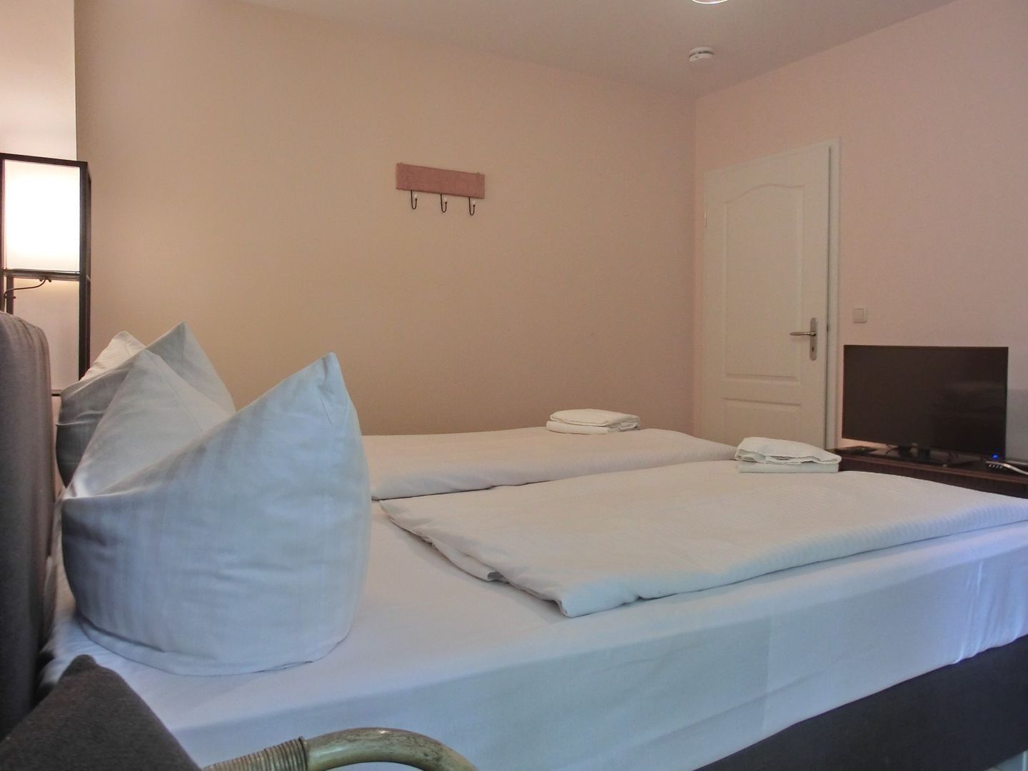 A hotel room with two beds, a television, and a door.