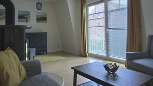 Una sala de estar con sofá, mesa de centro, chimenea y vistas a un edificio a través de amplios ventanales.