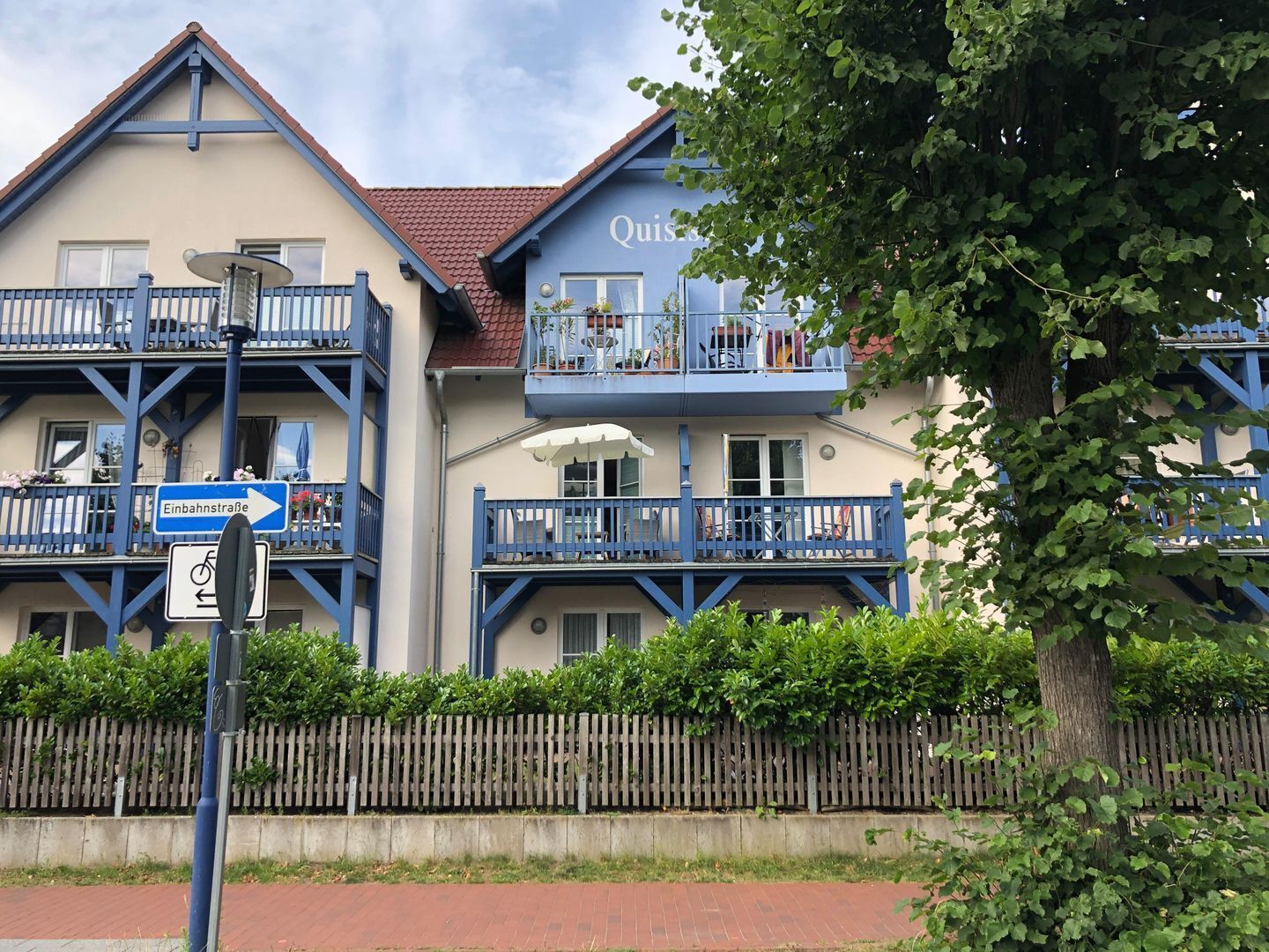 A building with balconies, a sign indicating 'Einbahnstraße', and a bicycle symbol.