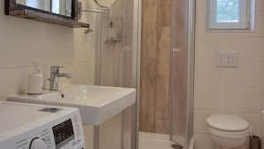 A modern bathroom with a glass-enclosed shower, a sink, a toilet, and a washing machine. - Apartment KWi 59 OG - 2-room apartment for 2 pers. with WLAN (Gelbensande)