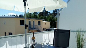 En tagterrasse med et bord, stole, en vinflaske og et glas vand.