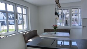 A modern kitchen with a built-in island, large windows, and a view of residential buildings.