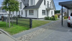 A two-story house with a grey roof, white exterior walls, and a balcony.