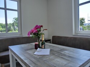 Une pièce avec une table en bois, un vase rempli de fleurs roses, une bouteille de champagne et une bougie.