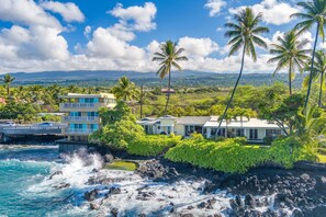 Situated on a rocky shoreline, this coastal property offers ocean views and a scenic backdrop of distant mountains.