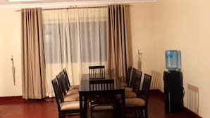 Un espace repas comprenant une table et des chaises, un distributeur d’eau et un radiateur.