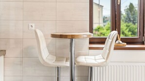 Una habitación moderna con una mesa redonda y dos sillas, un ventanal con vistas a zonas verdes y un radiador.