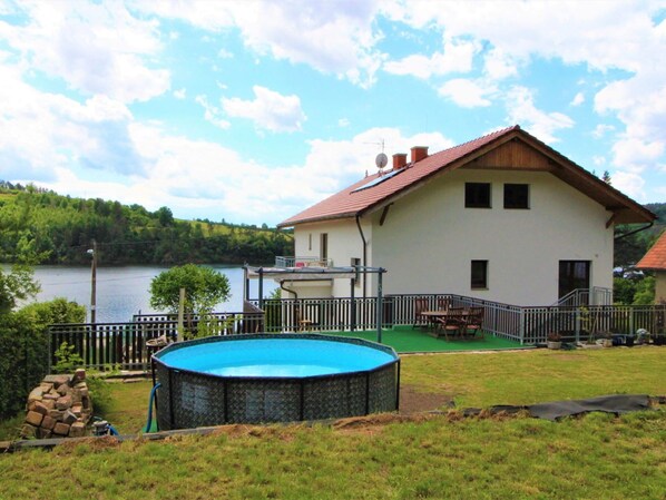 Una casa con piscina, terraza y vistas al lago.