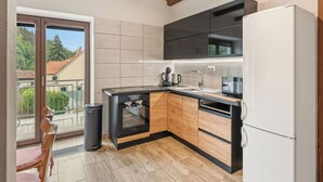 Une cuisine moderne équipée d’un four encastré, d’un réfrigérateur et d’une fenêtre donnant sur un quartier résidentiel.