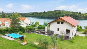 Une maison avec une piscine, un patio couvert et une vue sur un lac.