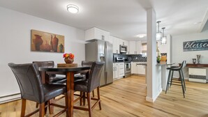 A modern kitchen with white cabinets, stainless steel appliances, and a wooden dining table with chairs. - Cozy newly remodeled home close to major amenities  in Connecticut a (Middletown)
