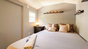 Un dormitorio con cama, mesita de noche y ventana.