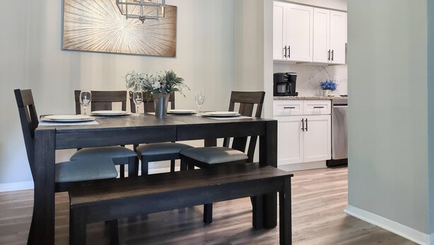 A dining area with a dark wooden table, four chairs, and a bench. A potted plant is on the table. - Idyllic Central Raleigh condo-3br/2bath (Raleigh)